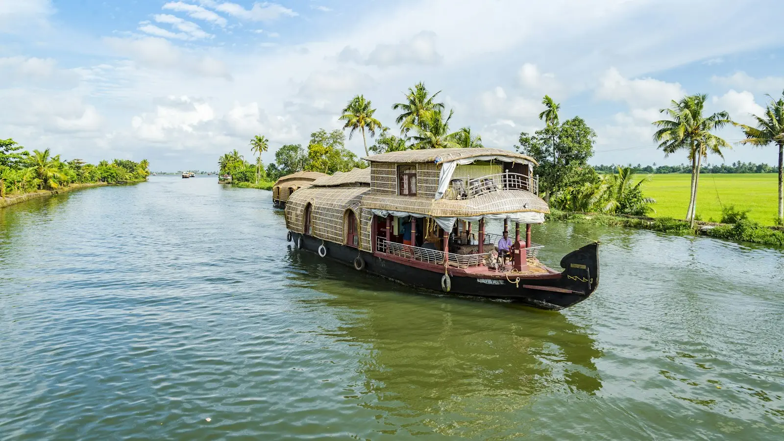 A houseboat on palm-lined backwaters under a blue sky