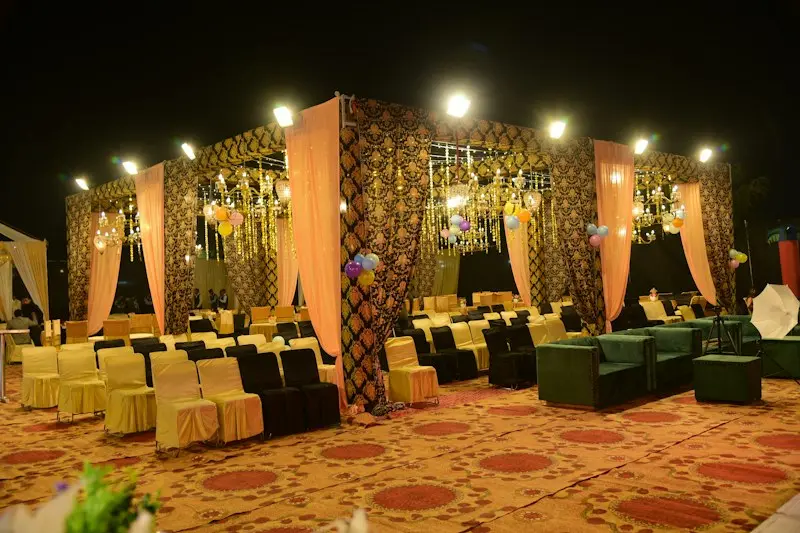 A lit outdoor banquet area with fabric pavilions, sofas and chairs
