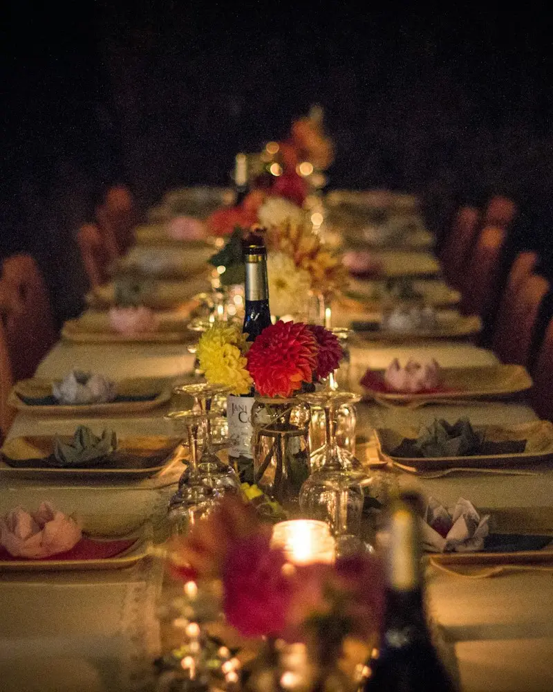 A long candlelit dinner table set with flowers and small lamps
