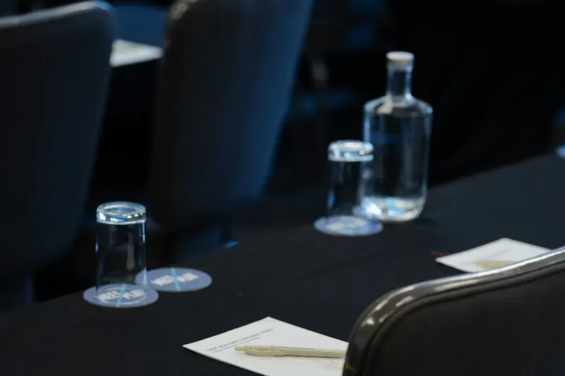 A conference room with dark tables, notepads and water bottles set out