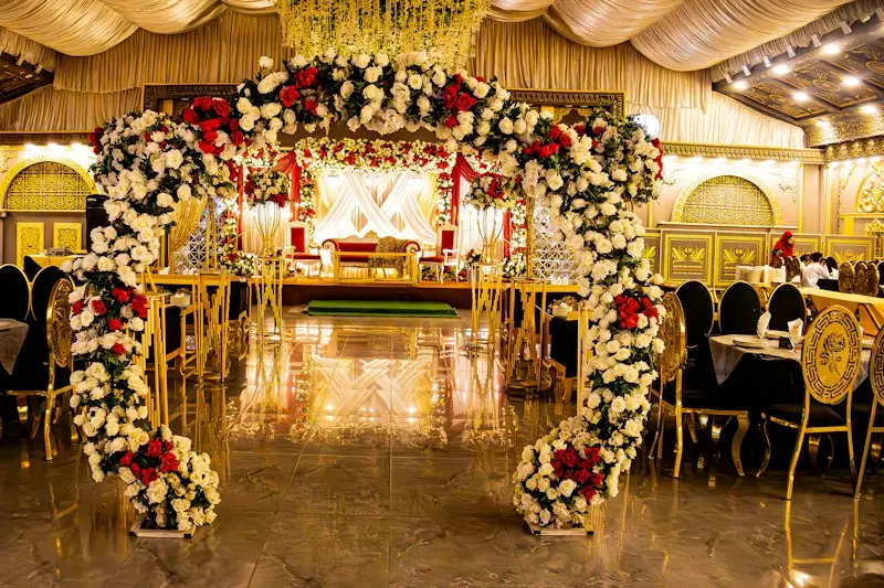 A banquet hall entrance framed by a tall arch of red and white flowers