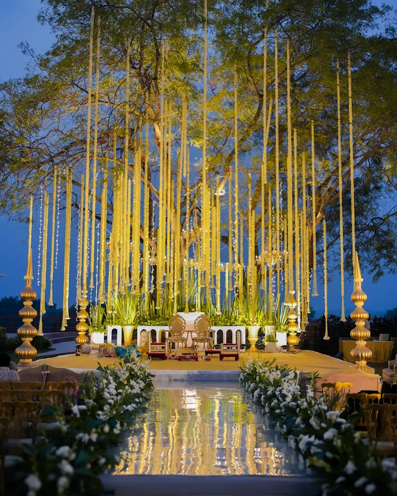 A lit stage under tall strands of marigold garlands at dusk